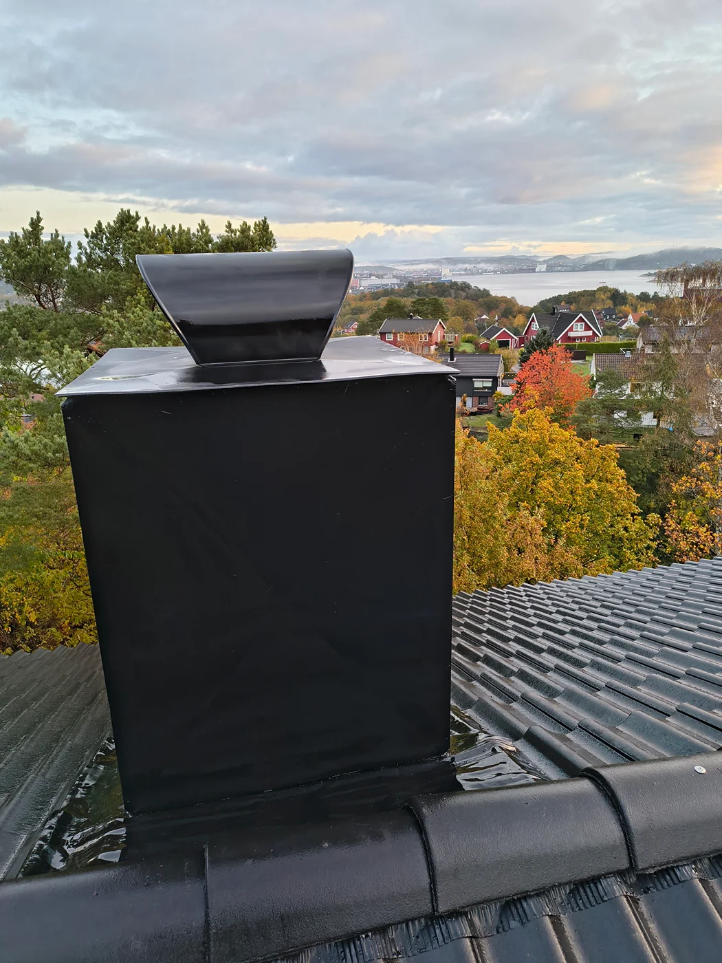 Black chimney hood on tiled residential roof