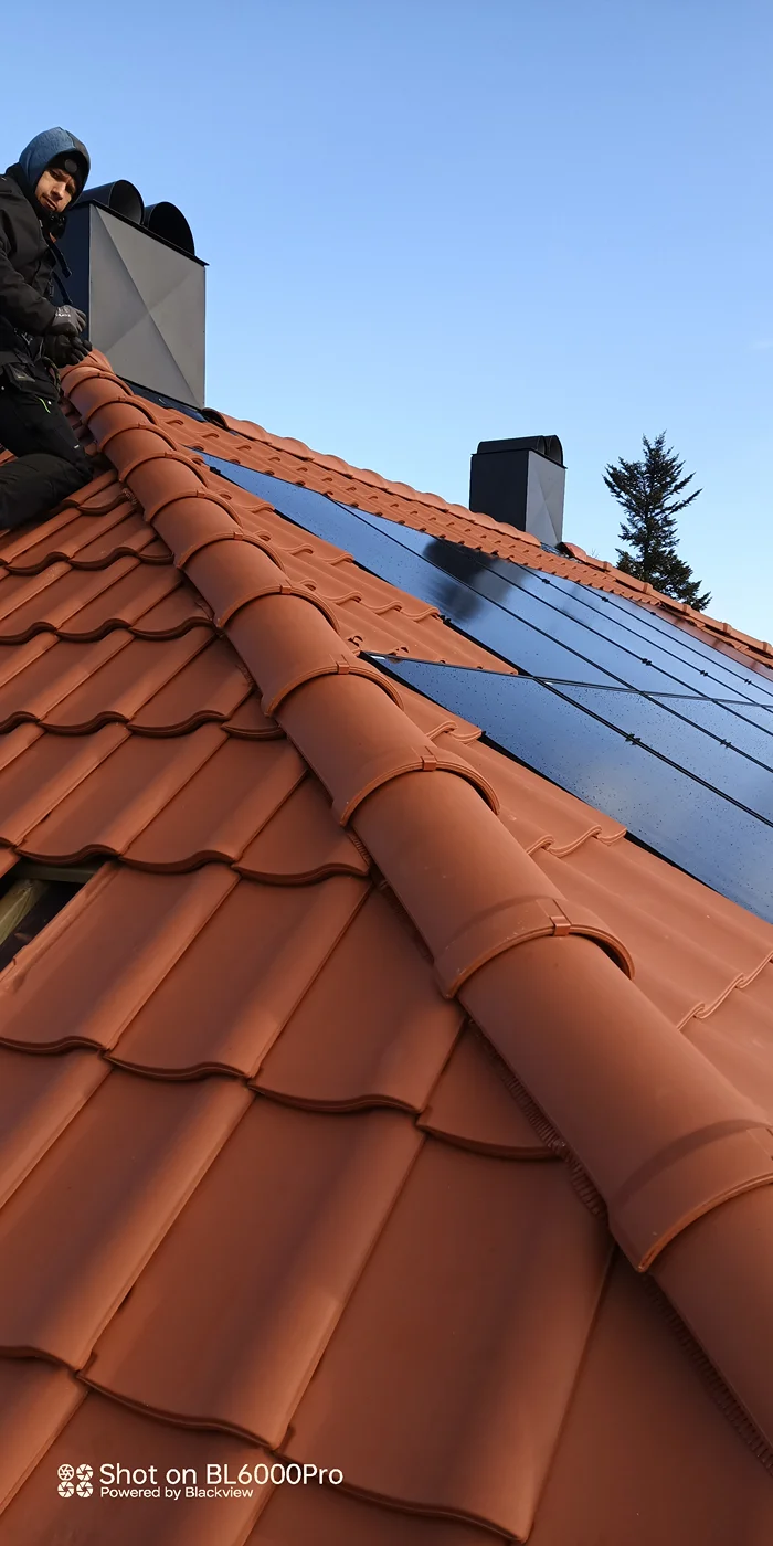 Worker installing solar panels on residential roof