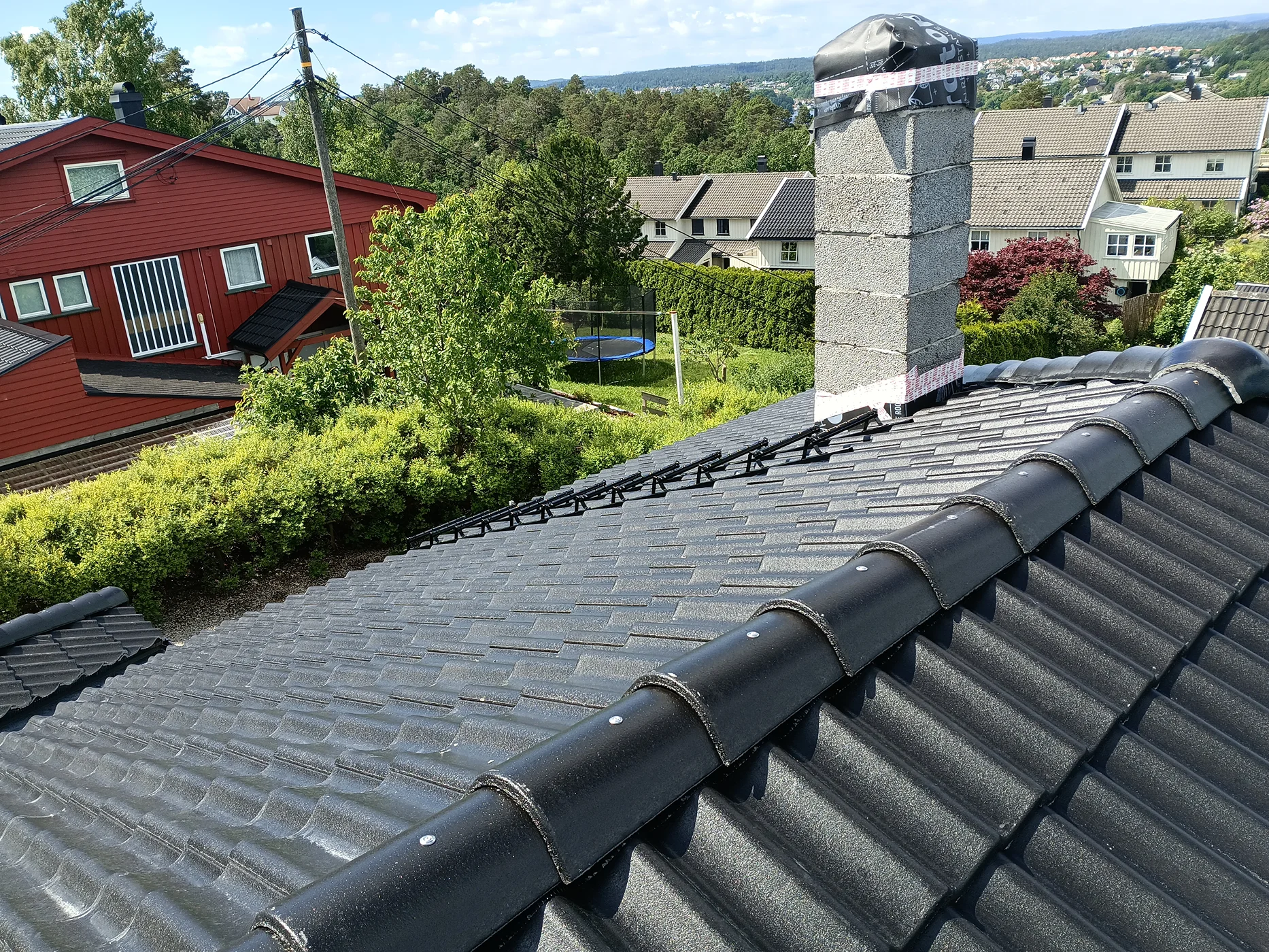 Modern roof installation with dark tiles and ridge vents