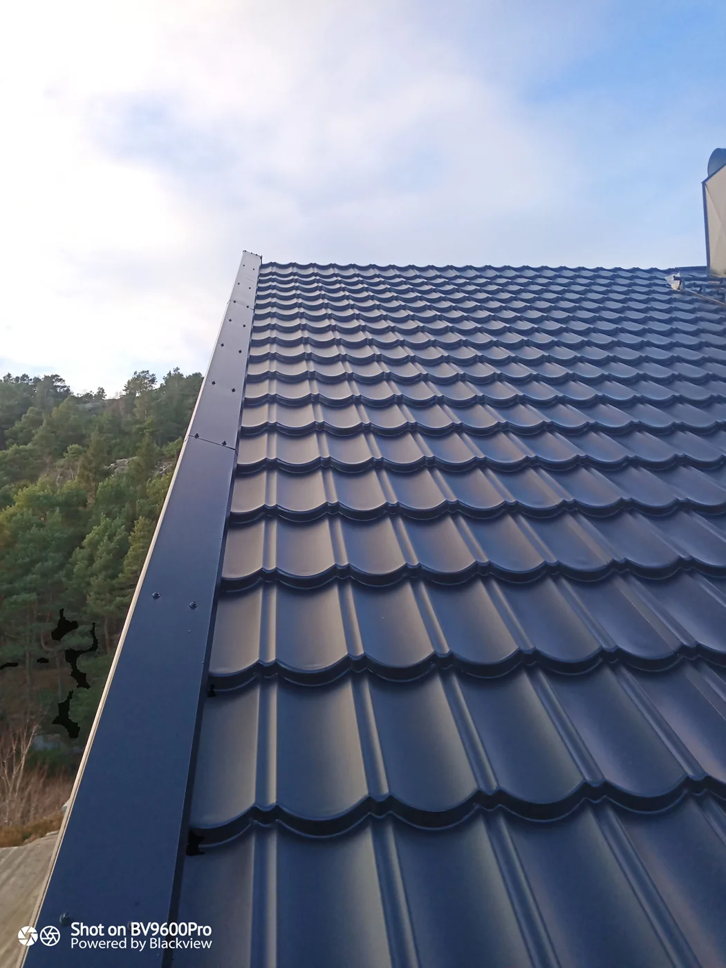 Dark metallic wavy roof tiles installed
