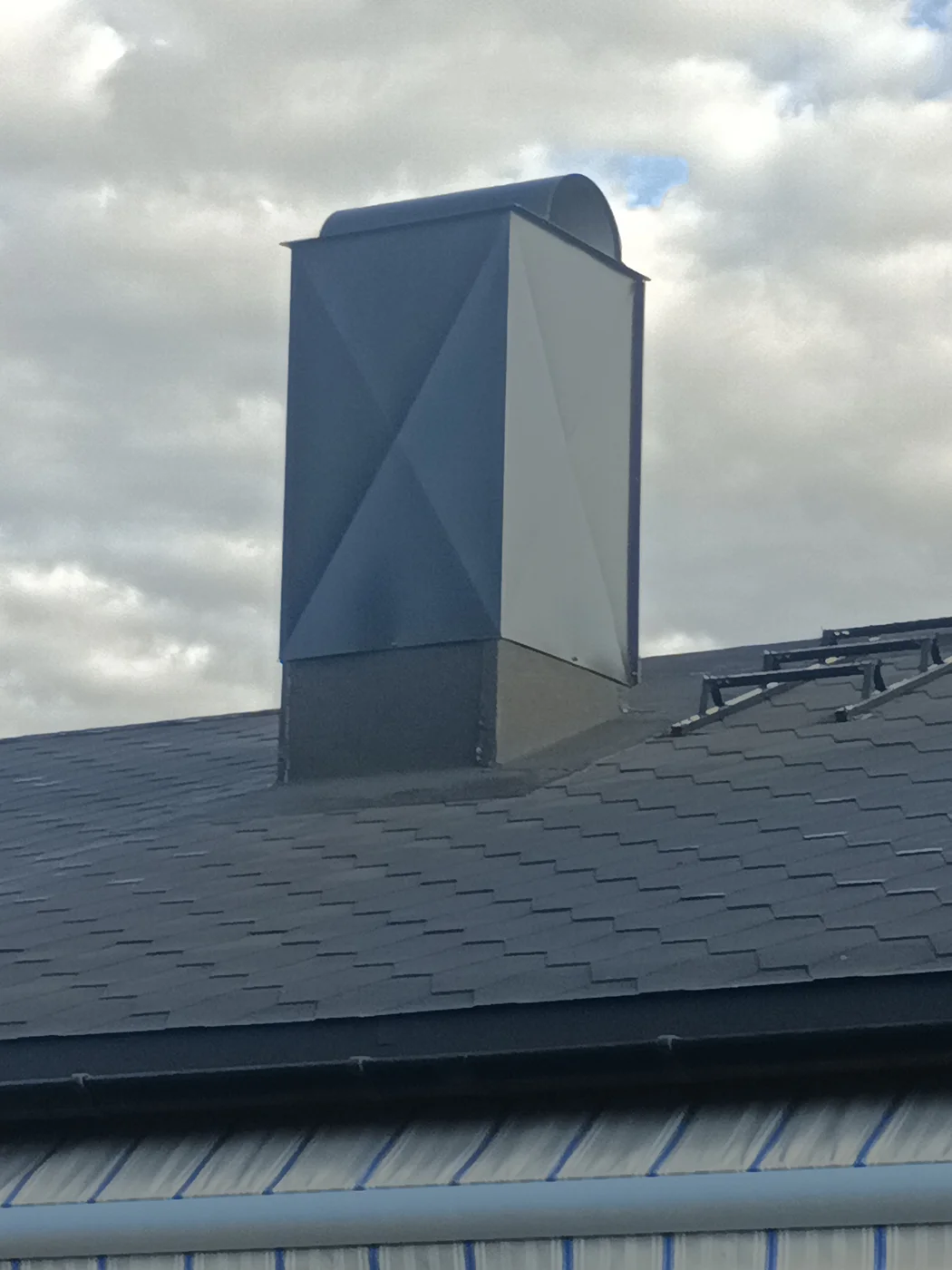 Modern chimney on dark tile roof