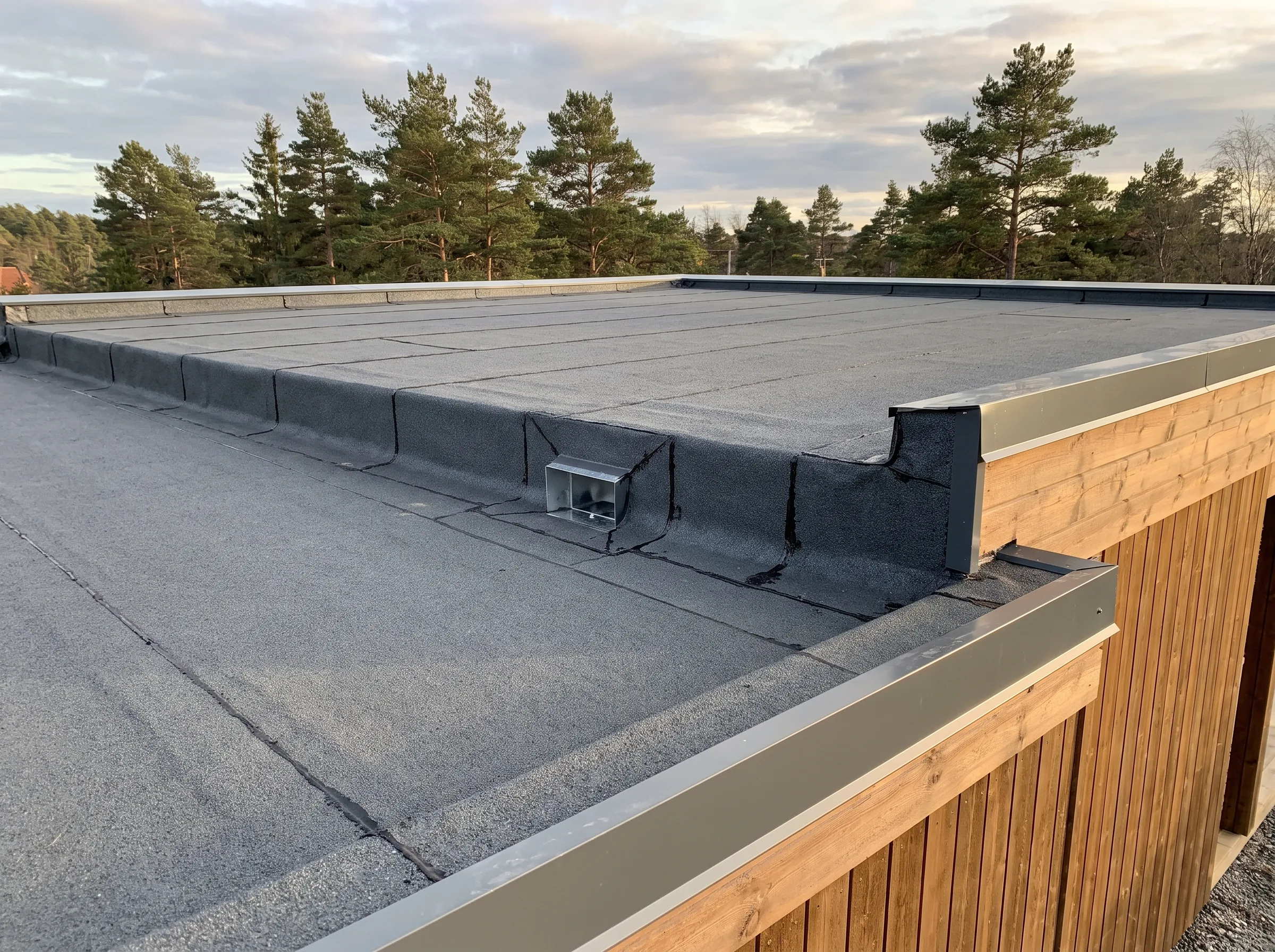 Flatt tak med takpapp i god stand som viser detaljer av kanten og veggen