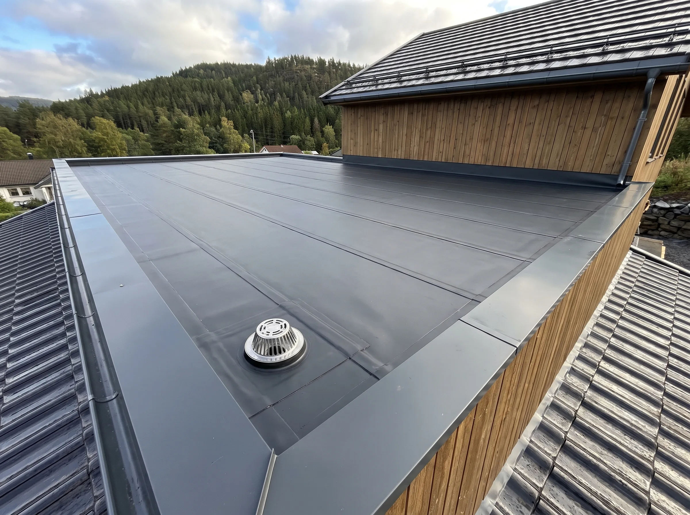 Tak med flat tak og ventilasjonsanlegg, med trepanel i bakgrunnen